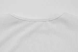 Gros plan sur la texture du tricot côtelé blanc et les coutures de l'encolure ronde