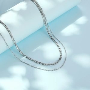 Double-layered silver stainless steel necklace with Figaro and fine link chains on blue background