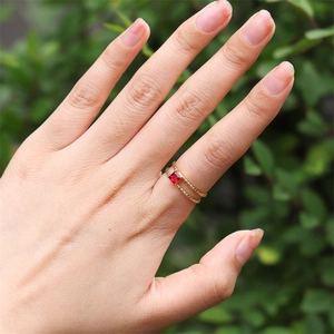 Detail of 18K gold-plated double-band ring with a square red zircon on a female hand