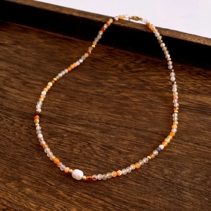 Detail of beaded necklace with a large baroque pearl and warm-toned natural stones
