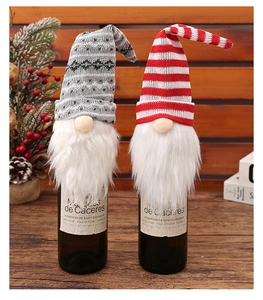 Close-up of knitted Christmas gnome wine bottle covers with plush white beards and festive hats