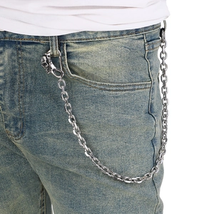 Detail of silver skull trouser chain with metallic link hanging on blue denim jeans