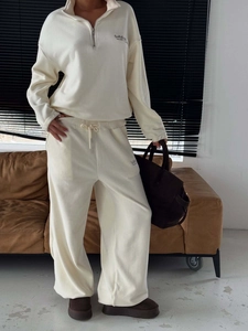 Two-piece cream fleece set with half-zip sweatshirt and wide-leg sweatpants on a sofa