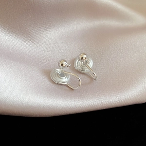 Detailed macro view of silver clip-on earrings with silicone pads on silk fabric