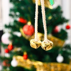 Detailaufnahme goldener Weihnachtsglöckchen mit rustikalem Hanfseil am Baum