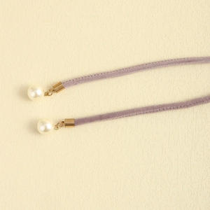 Detail of lavender velvet belt featuring gold metal tips and elegant white pearl pendants