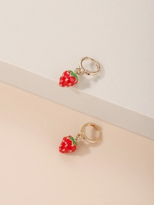 Close-up of creative strawberry earrings with red enamel and golden hoops on a beige base