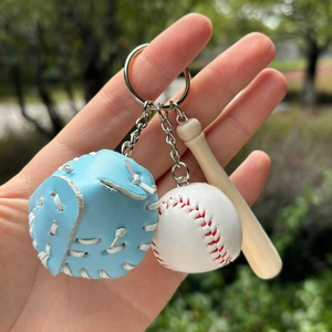 Detail of mini baseball glove and bat keychain featuring blue leather and wood texture