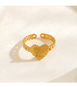 Detailed close-up of golden heart ring with Love You engraving on silk fabric