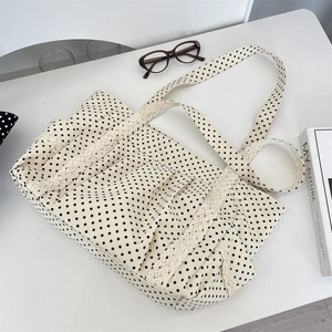 Close-up of cream canvas tote bag with black polka dots and white lace trimmings