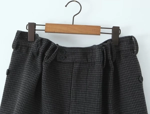 Detail of high-waist plaid skirt featuring double buttons and houndstooth wool fabric