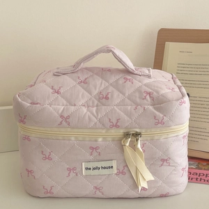 Close-up of pink quilted makeup bag with ribbon bow patterns and soft fabric texture