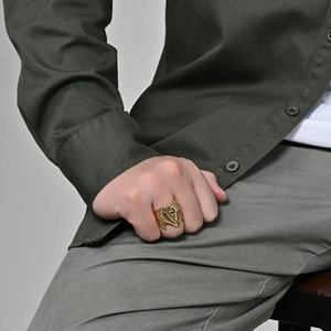 Men's oversized vintage gold metal cross shield signet ring worn as a statement piece