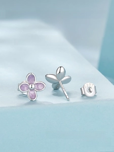 Detail of S925 sterling silver lilac earrings with purple enamel finish on blue surface