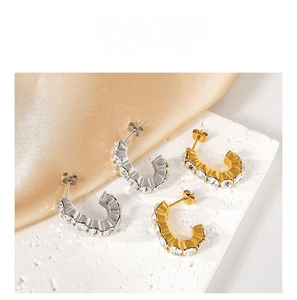 Detail view of gold and silver C-shaped earrings with inlaid cubic zirconia on satin base