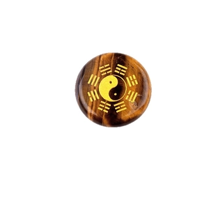 Round tiger eye stone disc with golden yin yang bagua symbol on white background