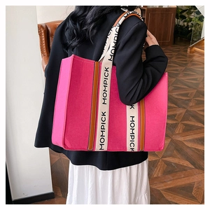 Detail of a large pink felt tote bag with MOMPICK lettered straps worn by a model