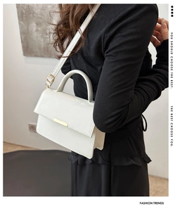 Detail view of white crossbody bag showing side thickness and gold metal clasp