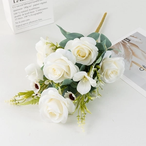 Elegant white silk rose bouquet with greenery and small blossoms on white background