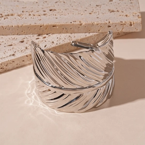 Detailed close-up of textured leaf pattern on silver wide cuff bracelet with light shadows