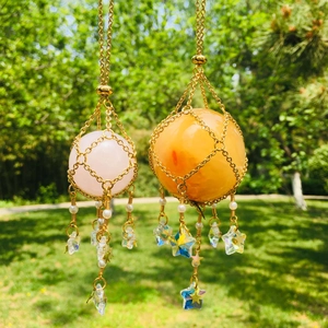 Detail of gold cage pendants with pink and orange crystals featuring pearl and star charms