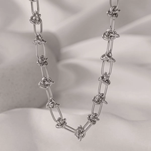 Detailed close-up of a silver long oval link necklace with elegant knot fasteners