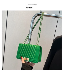 Detail of green crossbody bag with V-shaped quilting and gold chain strap