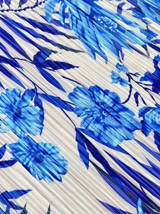 Macro shot of pleated fabric with blue floral print showing fine vertical texture