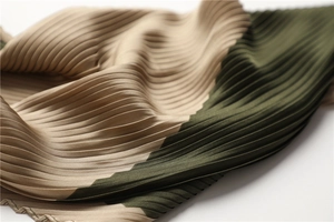 Macro detail of pleated silk scarf showing gold and dark green color-block texture