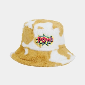 Close-up of yellow and white cow print bucket hat with plush faux fur and POW embroidery