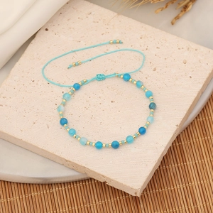 Macro detail of blue beads and woven adjustable rope bracelet on a stone surface