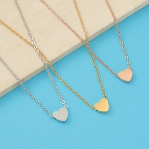 Detailed view of minimalist heart pendants in silver, gold, and rose gold stainless steel