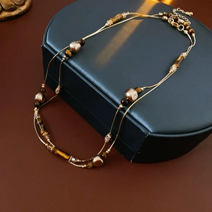 Detailansicht der zweilagigen Kette mit Goldkette, Tigerauge-Stein und Kunstperlen