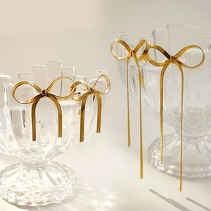 Detailed view of elegant gold bow earrings featuring long tassel and short stud styles