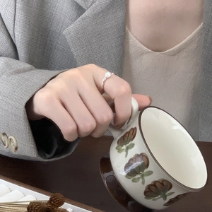 Close-up of a 925 silver minimalist pearl ring worn while holding a vintage ceramic cup