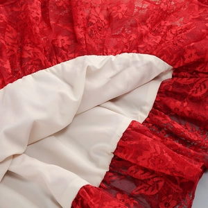 Detailed close-up of red floral lace fabric with smooth beige lining on a slim dress