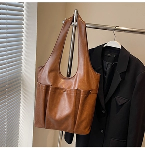 Brown leather tote bag featuring pleated texture and multiple functional exterior pockets