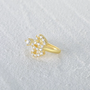 Macro detail of a golden snake-shaped ear cuff with pave-set white cubic zirconia crystals