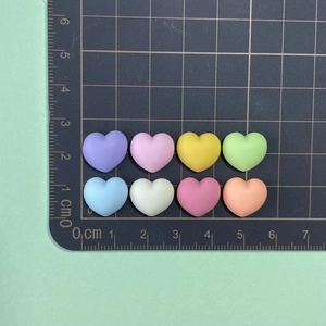 Macro detail of eight colorful 1.5cm resin heart charms for DIY jewelry and nail art
