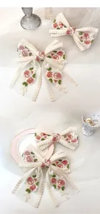 Detailed close-up of lace bow hair clips featuring elegant pink rose floral embroidery