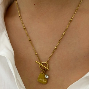 Golden T-bar necklace with heart pendant and Mom engraving on female model