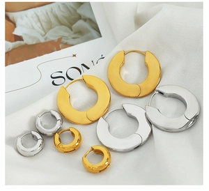 Detailed view of thick polished gold and silver hoop earrings in three various sizes