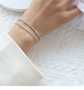 Detail of silver double-layer bracelet with sparkling zircons and delicate bead chain