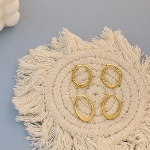 Detailed shot of gold hoop earrings set on a white textured mat with polished finish