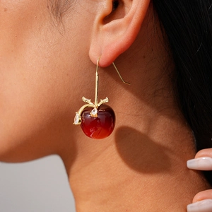 Détail d'une boucle d'oreille cerise en résine rouge avec crochet doré sur modèle