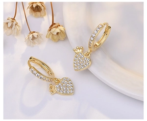 Macro shot of gold heart-shaped earrings with crown detail and white zircon inlay