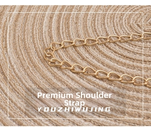 Close-up of polished gold metal chain strap on a rustic woven straw surface