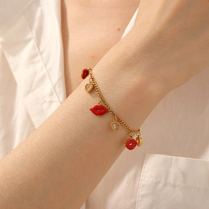 Golden heart rhinestone and red lip pendant chain bracelet worn on a female wrist