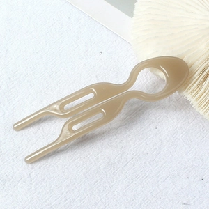 Close-up of light brown U-shaped minimalist hair pin fork on white textured fabric