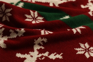 Macro shot of knitted fabric showing red, green and white Christmas reindeer and snowflakes